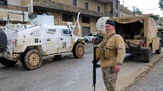 Um soldado libanês ao lado de um veículo da Unifil e de um caminhão do exército do Líbano, em meio à escalada das hostilidades entre Israel e o grupo Hezbollah, em 27 de março de 2026.