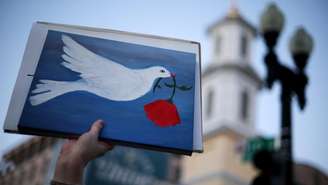 Um manifestante exibe um cartaz com o desenho da pomba da paz próximo à Casa Branca, em Washington, em 7 de abril de 2026.