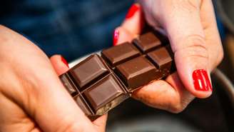 mãos de mulher quebrando barra de chocolate 
