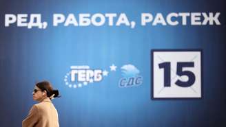 Uma mulher passa por um cartaz eleitoral do partido de centro-direita GERB em Sófia, Bulgária, em 14 de abril de 2026.