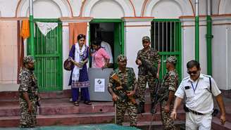 Agentes de segurança e funcionários eleitorais deixam a casa de um eleitor após recolherem sua cédula de votação, como parte da votação domiciliar durante as eleições para a Assembleia Legislativa de Bengala Ocidental, em Calcutá, em 23 de abril de 2026.
