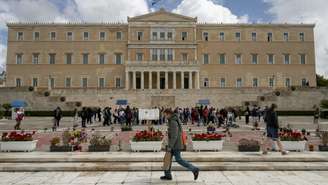 Pedestres diante do prédio do Parlamento grego, em Atenas, em 3 de abril de 2026.