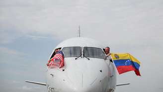 Pilotos do voo 3599 da American Airlines, partindo do Aeroporto Internacional de Miami com destino a Caracas, Venezuela, acenam com bandeiras venezuelanas e americanas antes da decolagem em um voo direto para a Venezuela, o primeiro entre os EUA e a Venezuela em sete anos, no Aeroporto Internacional de Miami, em Miami, Flórida, em 30 de abril de 2026.