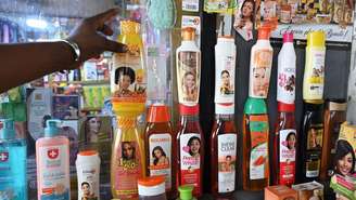 Diversos frascos de produtos de clareamento da pele, de diferentes fabricantes, expostos sobre uma mesa