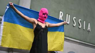 Uma integrante do coletivo ativista Pussy Riot segura uma bandeira ucraniana durante um protesto contra a participação da Rússia na Bienal de Veneza, em frente ao pavilhão russo, em 6 de maio de 2026, em Veneza.