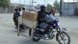 Moradores transportam seus pertences em motocicletas enquanto fogem de suas casas em Cité Soleil, após o agravamento dos confrontos entre gangues rivais na capital haitiana durante o fim de semana, em Porto Príncipe, no Haiti, em 11 de maio de 2026.