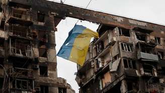 Em Mariupol, no leste da Ucrânia, uma bandeira ucraniana rasgada tremula diante de um prédio destruído. (Imagem ilustrativa)