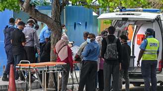 Equipes de emergência do Crescente Vermelho e policiais transferem os corpos de turistas italianos de uma lancha da polícia para uma ambulância em Malé, nas Maldivas, em 19 de maio de 2026.
