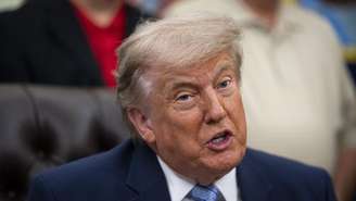 O presidente dos EUA, Donald Trump, senta em uma cadeira de couro e fala
