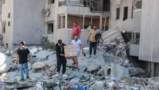 Moradores inspecionam os danos no local de um ataque israelense noturno na cidade de Tiro, no sul do Líbano, em 23 de maio de 2026.