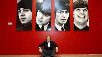 Paul McCartney na frente de quadro dos integrantes dos Beatles