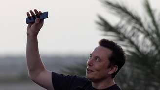 Elon Musk levanta seu telefone para o céu durante uma coletiva de imprensa na base Starbase da SpaceX, em Brownsville, Texas, EUA, em 25 de agosto de 2022.