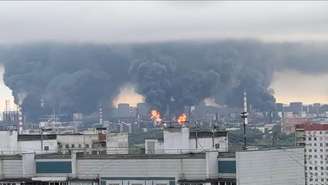 Densas colunas de fumaça, acompanhadas por chamas, se elevam de uma refinaria de petróleo em Moscou.