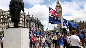 Pessoas passam diante da Torre Elizabeth, o Big Ben, durante a 4ª Marcha Nacional pela Reintegração, em Londres, ato que marcou os dez anos do referendo do Brexit e defendeu maior aproximação entre o Reino Unido e a União Europeia, em 20 de junho de 2026.