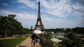 Pessoas se protegem do sol com um guarda-chuva perto da Torre Eiffel, enquanto as temperaturas sobem em Paris durante a segunda onda de calor que afeta grande parte da França. Em 20 de junho de 2026.