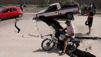 Um homem de motocicleta passa por estrada danificada após terremotos atingirem a Venezuela