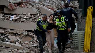 Agentes da polícia municipal ajudam uma vítima ferida de um edifício que desabou após um terremoto ocorrido em Caracas, em 24 de junho de 2026.