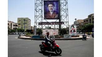 Pessoas passam de motocicleta por um banner com a foto do Líder Supremo do Irã, Mojtaba Khamenei, em Teerã, Irã, em 28 de junho de 2026