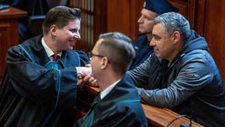 Imagem de arquivo. O réu ucraniano Volodymyr Zhuravlyov (à direita) aperta a mão de seu advogado, Tymoteusz Paprocki (à esquerda), em uma sala de audiências do Tribunal Regional de Varsóvia, na Polônia, em 17 de outubro de 2025.