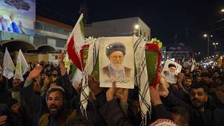 Procissão simbólica noturna no Irã, com a multidão carregando bandeiras e fotos do ex-líder supremo do Irã, o aiatolá Ali Khamenei