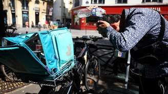 Entregador da Deliveroo se refresca com uma garrafa de água, enquanto uma onda de calor atinge a França, em 18 de junho de 2026.