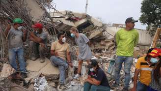 Moradores se reúnem enquanto equipes de resgate vasculham escombros em Caraballeda, no estado de La Guaira, após o duplo terremoto ocorrido na Venezuela. 9 de julho de 2026