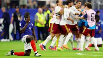 Dayot Upamecano, da França, abatido após a partida e a eliminação de sua equipe, enquanto jogadores da Espanha celebram a classificação para a final da Copa do Mundo, em 14 de julho de 2026, no Dallas Stadium, Arlington, Texas, EUA.