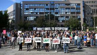 Ativistas da Flotilha para Gaza exibem cartaz com dizeres “UE, pare de comprar o que Israel rouba” entre outras frases em Bruxelas, em 17 de junho de 2026.
