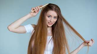 Concept of hair loss. Close up portrait of unhappy sad stressed young woman with long dry brown hair, isolated on grey background