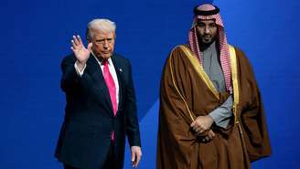 O presidente dos EUA, Donald Trump (à esquerda), e Mohammed bin Salman, príncipe herdeiro da Arábia Saudita, são vistos no palco durante o Fórum de Investimento EUA-Arábia Saudita no Kennedy Center em Washington, em 19 de novembro de 2025. 