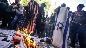 Manifestantes queimam bandeiras dos Estados Unidos e de Israel durante um ato em Caracas, em 24 de julho de 2026, contra a presença e a influência dos dois países na Venezuela, um mês após os terremotos de 24 de junho.