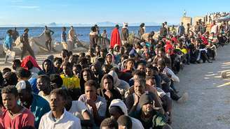 Centenas de migrantes foram fotografados em fila em uma praia em Ceuta para receber ajuda humanitária