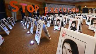 Em um protesto realizado em Roma, em 16 de julho de 2026, manifestantes iranianos exibem letras formando a frase "Parem as execuções" junto a fotos de opositores mortos pelo regime iraniano.
