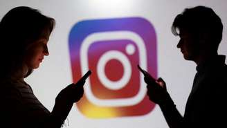 Adolescentes posam para uma foto segurando smartphones diante de um logotipo do Instagram nesta imagem ilustrativa produzida em 11 de setembro de 2025.
