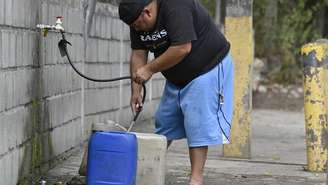 Homem coleta água potável em recipientes de plástico devido à falta de abastecimento em Tegucigalpa, capital de Honduras, em 19 de agosto de 2026.