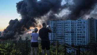 Moradores observam fumaça provocada por ataque de drones russos em Kiev, capital da Ucrânia, em 20 de agosto de 2026.