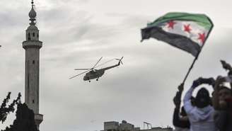 Helicóptero militar lança flores e confetes sobre multidão comemorando os dez anos da vitória de forças rebeldes sobre o exército de Bashar al-Assad em Idlib, Síria, em 28 de março de 2025.