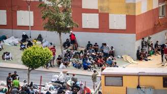 Migrantes aguardam na calçada no bairro de Loma Colmenar, em Ceuta, em 27 de agosto de 2026.