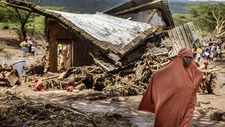 Mulher caminha por uma área de casas destruídas após enchentes repentinas atingirem Mai Mahiu, no Quênia, em 30 de abril de 2024.