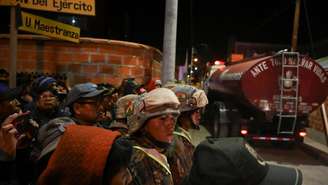 Pessoas que buscam por parentes desaparecidos e moradores da região aguardam enquanto militares formam um cordão de segurança após explosões que deixaram mortos e feridos no Regimento de Artilharia Mecanizada "Bolívar", em Viacha, Bolívia, em 4 de setembro de 2026.