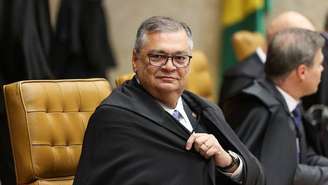 Flavio Dino com a toga de ministro do STF sentado ao lado de Mendonça no plenário da Corte