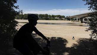 Um ciclista passa às margens do rio Loire, em Orléans, na França, em 20 de julho de 2026, em um trecho onde o leito do rio secou devido às repetidas ondas de calor que atingiram o país durante o verão europeu.