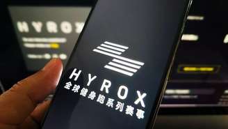 Mulher segura um telefone celular mostrando a marca Hyrox