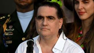 Alex Saab veste uma camisa branca e está de pé diante de um microfone