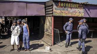 Policiais sul-africanos cercam um estabelecimento onde dez pessoas morreram em um tiroteio na madrugada deste domingo (27), no município de Lwandle, nos arredores da Cidade do Cabo.