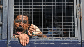 Um manifestante grita palavras de ordem de dentro de uma viatura policial após ser detido durante protesto em Mumbai