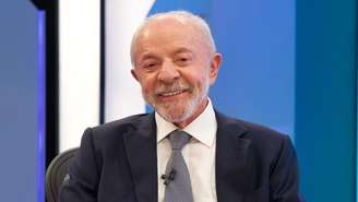 Lula sorrindo para foto, sentado em bancada da Globo