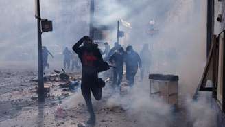 Manifestante corre durante uma manifestação contra o alto custo de vida, em Paris, neste sábado (17), no âmbito de uma convocação nacional que reuniu diferentes grupos mobilizados pelo descontentamento social, entre eles ex-integrantes dos coletes amarelos, estudantes do ensino médio e universitários, ativistas ambientais e agricultores.