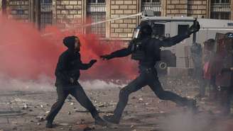 Um manifestante fica frente a frente com a tropa de choque francesa em meio a confrontos durante uma manifestação contra o custo de vida e o aumento dos preços dos combustíveis em Paris