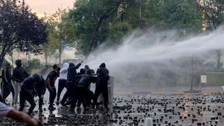 Manifestantes enfrentam unidades policiais durante um protesto contra o governo no centro de Tirana, em 17 de outubro de 2026.